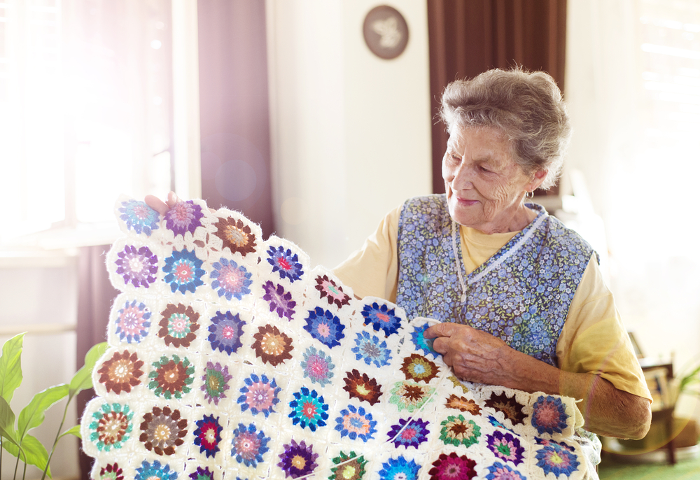 Elderly woman with a knitted blanket in assisted living suite